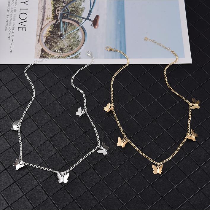 Two Gold Chain Butterfly Pendant Chokers for Women on top of a magazine.