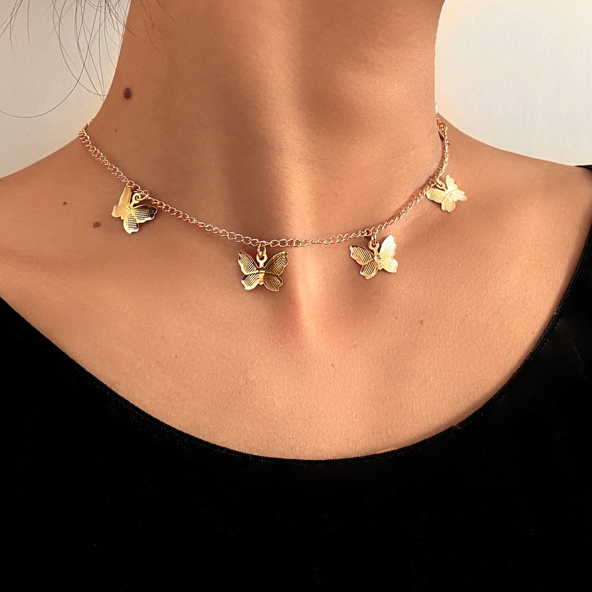 A woman adorned in a Gold Chain Butterfly Pendant Choker for Women with three delicate butterflies.