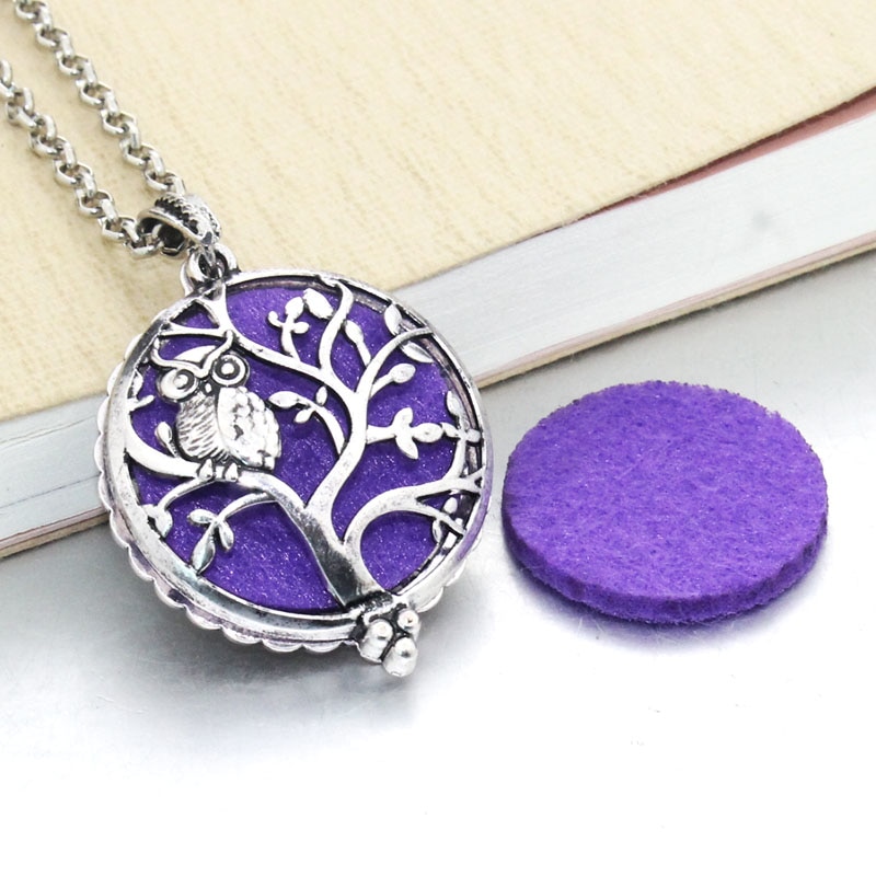 Aroma Essential Oil Diffuser pendant necklace with a purple background on a chain, lying next to a purple felt pad, embodying new fashion trends.
