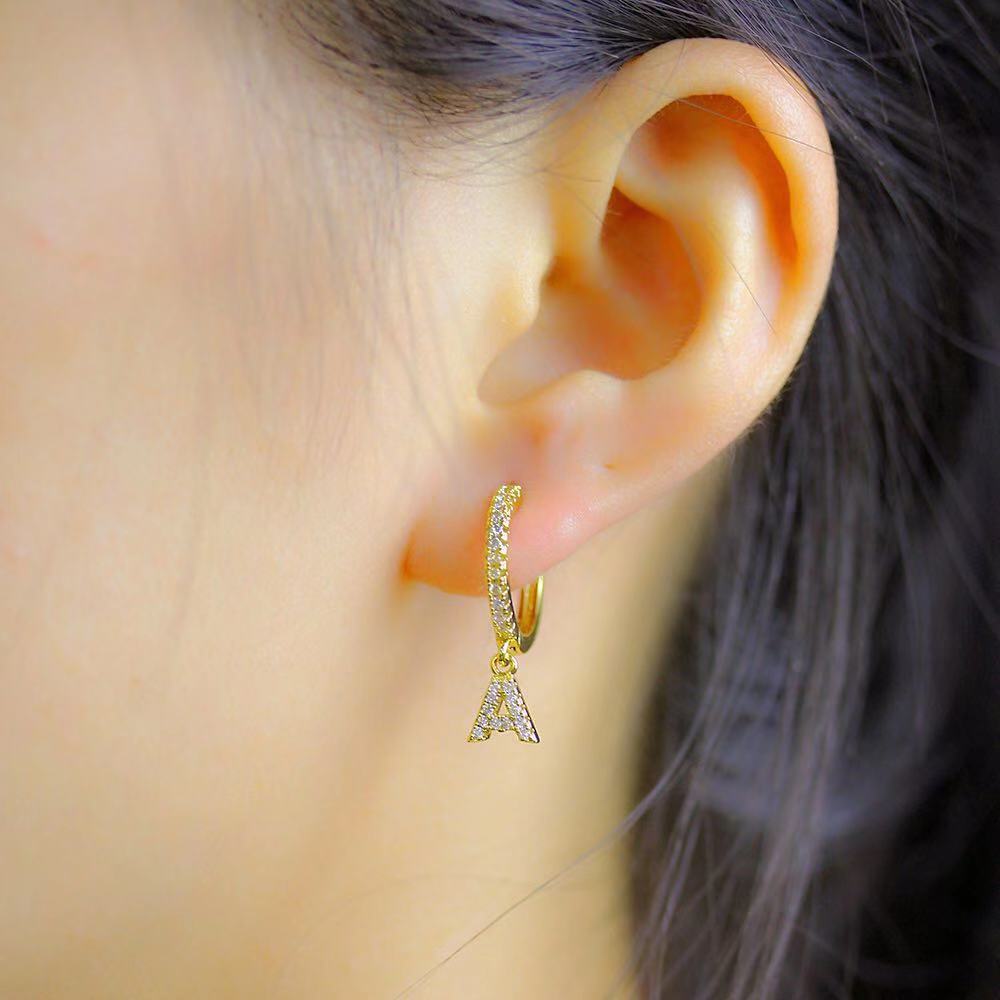 A woman's ear adorned with a Women's Initial Letter Hoop Earring.
