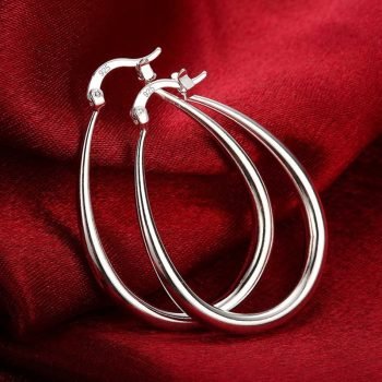 A pair of Women's 925 Sterling Silver Oval Hoop earrings on a red cloth.
