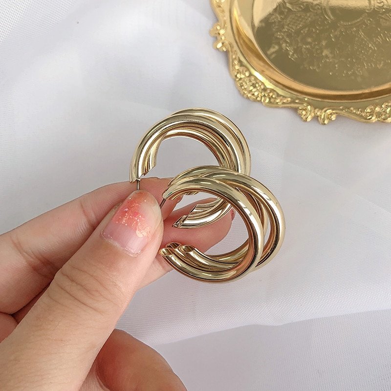 A person holding a pair of Women's Fashion Chunky Hoop Earrings, perfect for women's fashion.