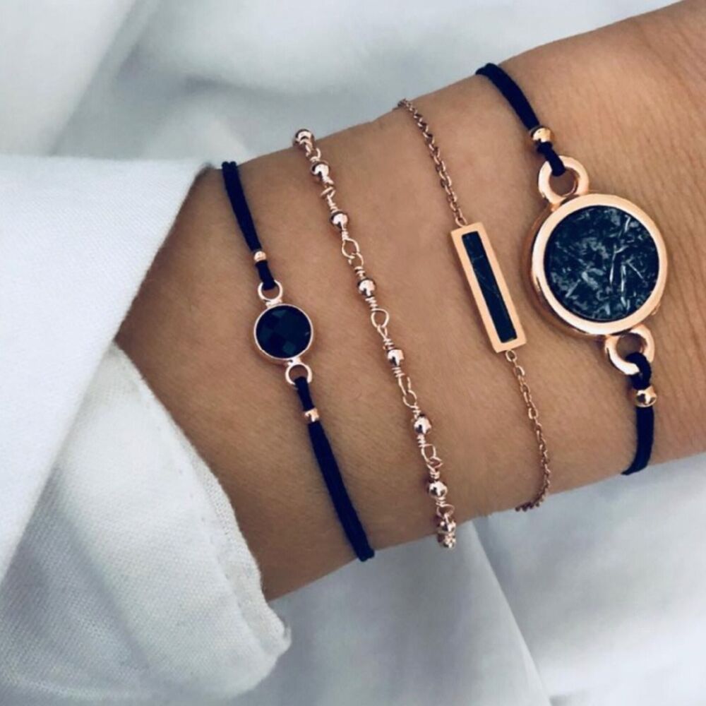 A wrist adorned with various bracelets, including a charm bracelet, a bangle with a circular feature, and the Bohemian Rope Chain Bracelet for Women, showcasing the latest in women fashion.