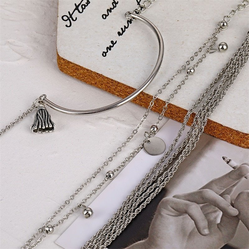 Assorted silver necklaces and a Women's Bohemian Tassel Round Bracelet, embodying the latest fashion trends, displayed against a white backdrop.