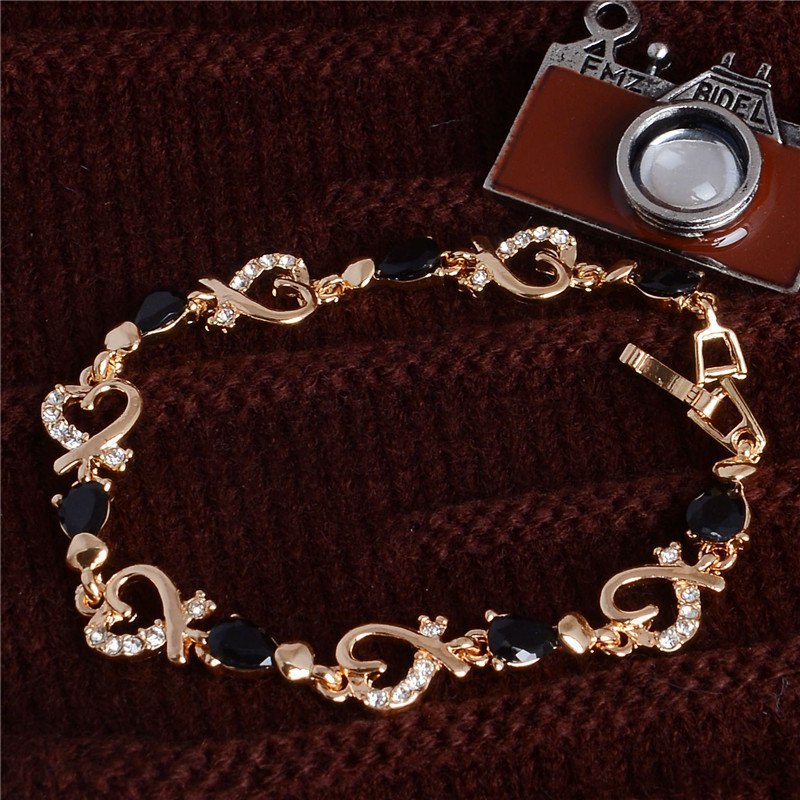 Women's Fashion Colorful Bracelets with heart-shaped links and black gemstone accents displayed on a brown fabric background, embodying the latest fashion trends.