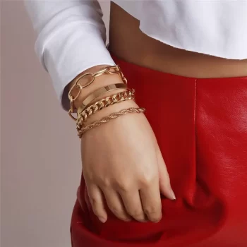 A woman wearing a red skirt and gold curb Cuban chain bracelets, adorned with the Curb Cuban Chain Bracelets Set for Women, 4 Pcs.