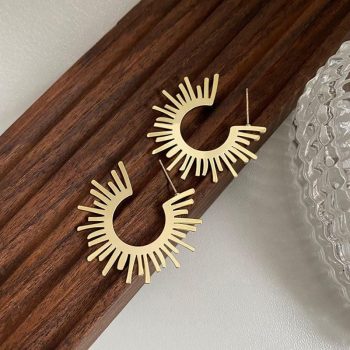 A pair of Chic Sunflower Hoop Earrings for Women, a trendy new fashion accessory, displayed on a dark wooden shelf.